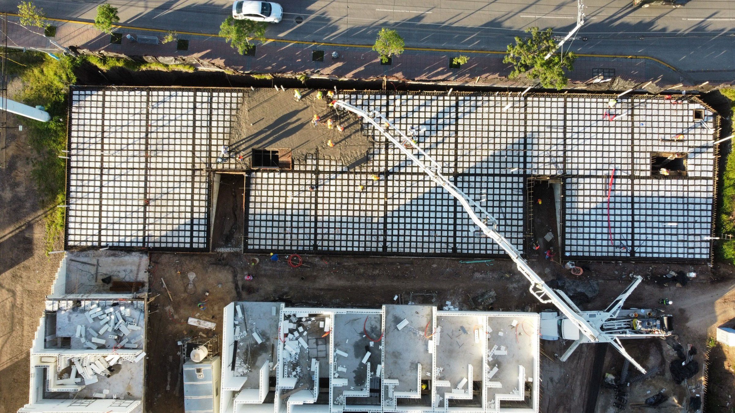 Aerial view of a construction site with a concrete pump placing a slab