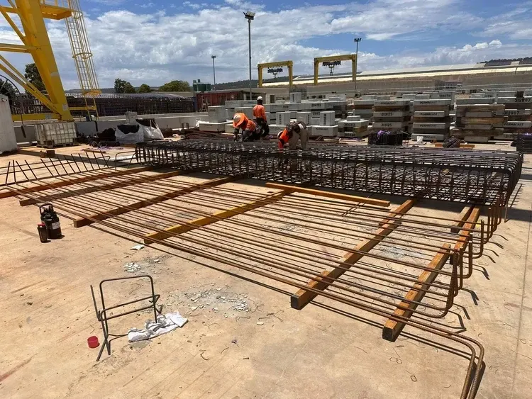 Crew fixing a large reinforcement mat on a precast yard
