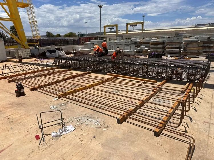 Crew fixing a large reinforcement mat on a precast yard
