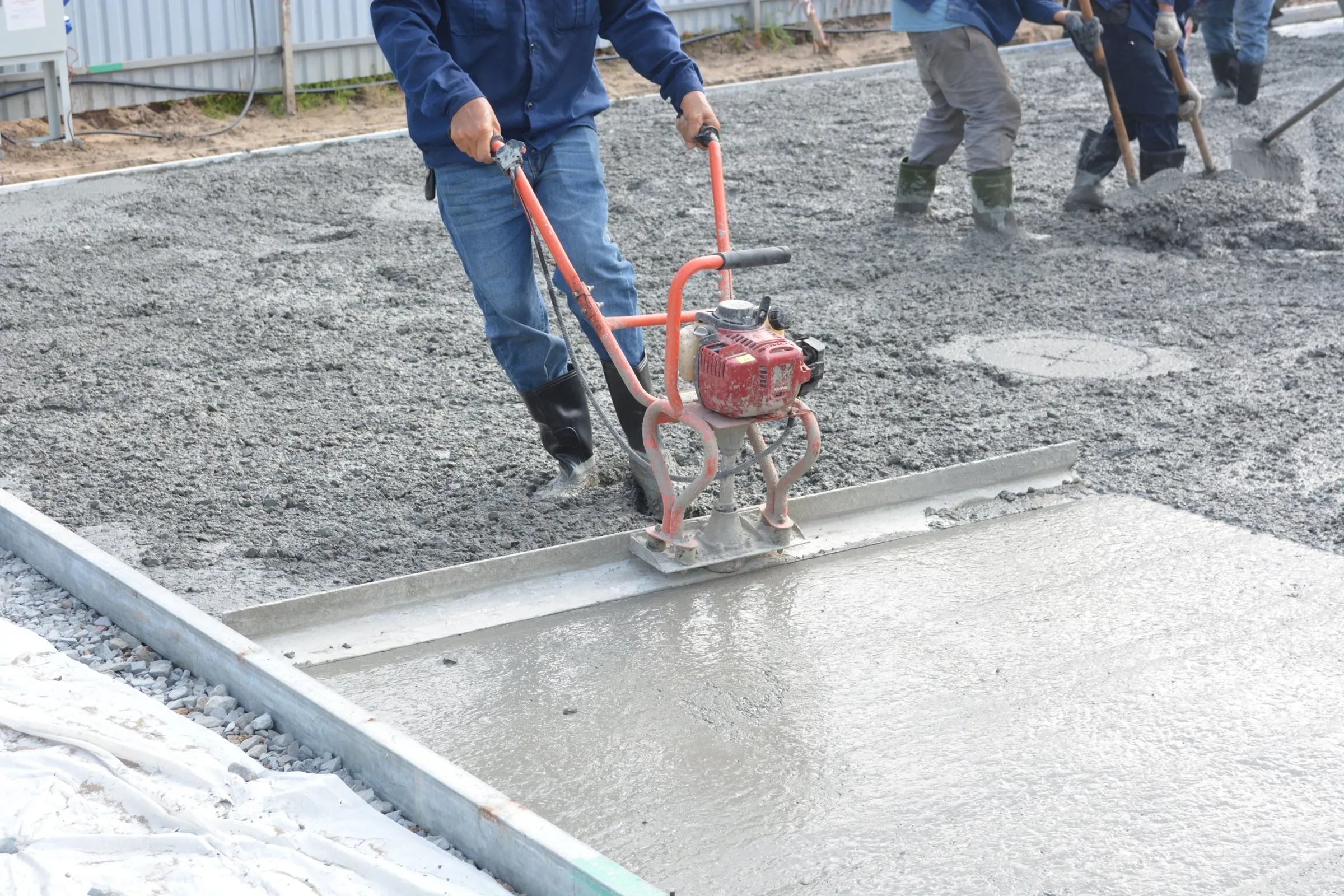 Workers screeding a freshly placed concrete slab